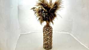 A corner with a white wall and a marble base, featuring a decorative woven vase with dried plants. - Petuna Cave Suites (Santorini)