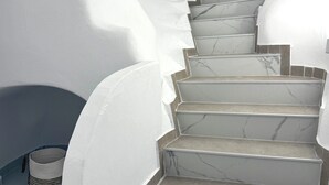 A staircase with white walls and marble steps. - Petuna Cave Suites (Santorini)