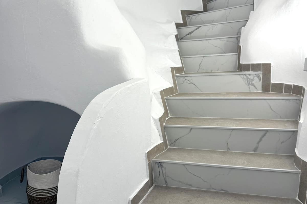 A staircase with white walls and marble steps.