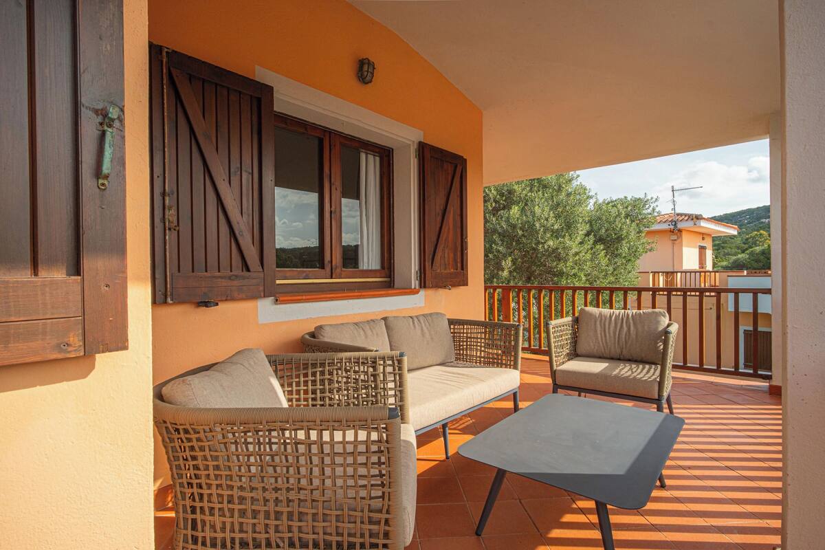 A balcony with wicker furniture, a table, and a view of the surrounding landscape.