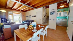Ein gemütliches Zimmer mit einem Holztisch, weißen Stühlen, einer Couch und einer Treppe, die in eine Küche führt.