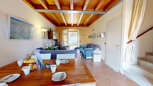Ein gemütliches Zimmer mit Holztisch, gedecktem Frühstück, einer Couch und einem Fernseher.