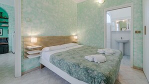 A bedroom with a bed, bedside tables, a nightstand, a mirror, and a bathroom with a sink. - GuestHost - A comfortable, welcoming 40 square meters apartment, perfect for four people, located on the second floor of a period building (NO elevator).The property is located near the Vittorio Emanuele I Bridge in a quiet residential area, well-connect (Turin)