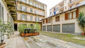 A courtyard with a stone floor, potted plants, and a building with multiple balconies and windows. - GuestHost - A comfortable, welcoming 40 square meters apartment, perfect for four people, located on the second floor of a period building (NO elevator).The property is located near the Vittorio Emanuele I Bridge in a quiet residential area, well-connect (Turin)