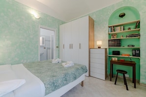 Un dormitorio con cama, armario, escritorio y estantería.