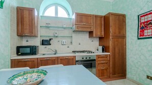 A kitchen with wooden cabinets, a microwave, a stove, and a sink. - GuestHost - A comfortable, welcoming 40 square meters apartment, perfect for four people, located on the second floor of a period building (NO elevator).The property is located near the Vittorio Emanuele I Bridge in a quiet residential area, well-connect (Turin)
