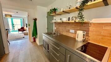 Een moderne keuken met een rvs aanrecht, een inbouwoven en een tegelachtergrond van baksteen.
