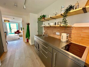 Una cocina moderna con encimera de acero inoxidable, horno empotrado y salpicadero de ladrillo.
