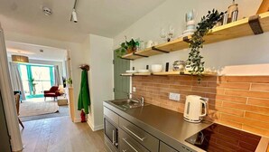 Una cocina moderna con encimera de acero inoxidable, horno empotrado y salpicadero de ladrillo.