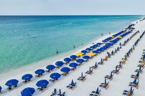 A beach with rows of blue and yellow umbrellas and sun loungers. - 8th floor Beachfront at Pelican, Stunning Ocean Views, 3 Pools, Beach Chairs (Destin)