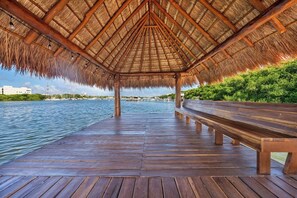 A wooden pier with a thatched roof structure, leading to a bench and a view of a marina. - Stylish, new apartment in Sac Bajo w/private dock (Isla Mujeres)