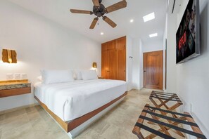 Ein Schlafzimmer mit Bett, Holzschrank, Deckenventilator und Fernseher an der Wand.