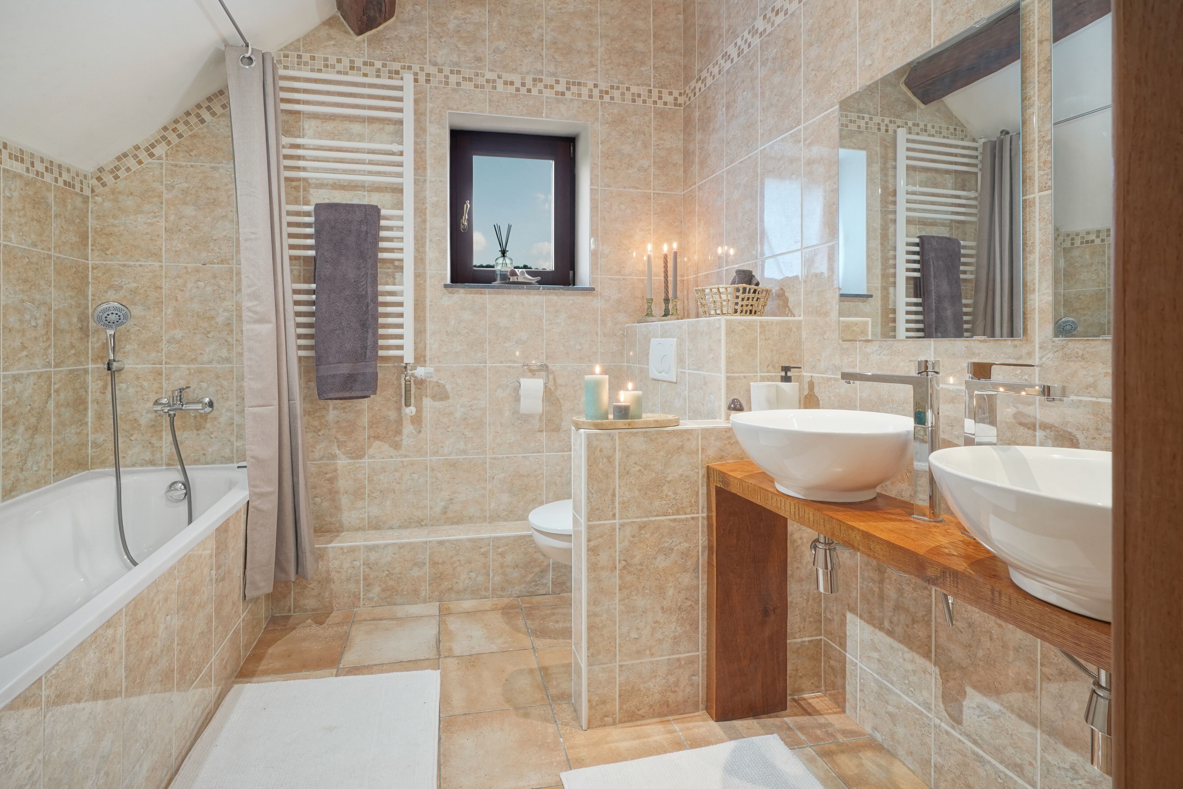 A modern bathroom with a bathtub, two sinks, a window, and a mirror.