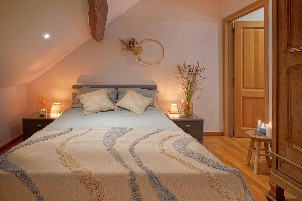 Un dormitorio con cama, mesitas de noche, una puerta de madera y un adorno en la pared.