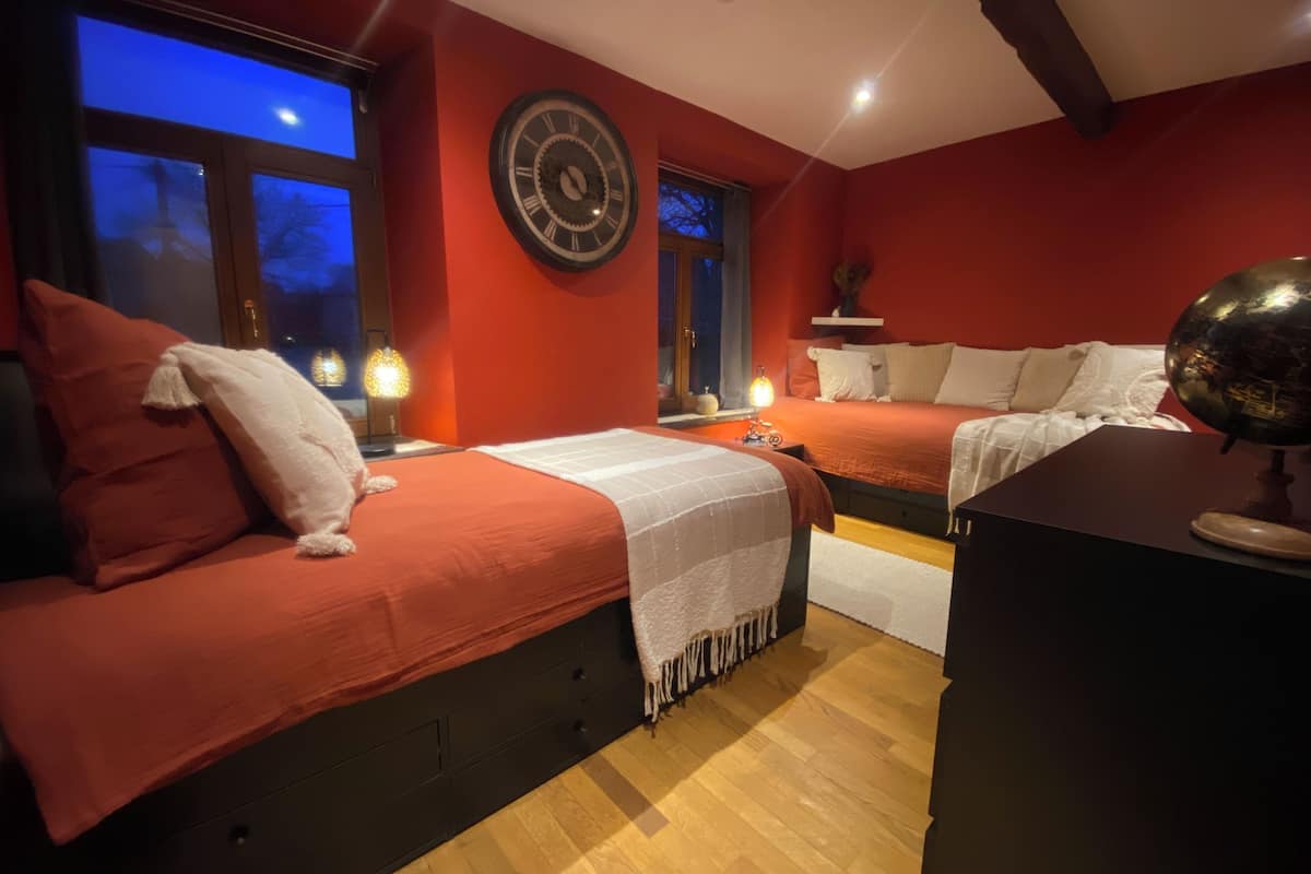Un dormitorio con dos camas, un reloj de pared grande, un globo terráqueo y una ventana con vista al cielo nocturno.