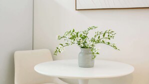 A minimalist room with a white round table, a white chair, and a vase with green plants. - Near Dtla Gem Stylish Private Suite w King bed (Monterey Park)
