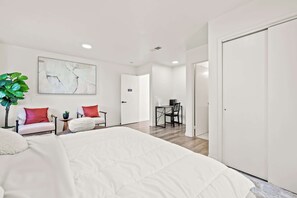 A modern hotel room with a large bed, two white sofas with red cushions, a desk with a chair, and a large abstract painting on the wall. - Near Dtla Gem Stylish Private Suite w King bed (Monterey Park)