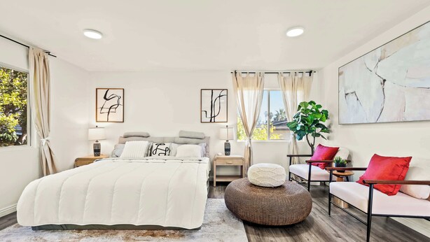 A modern bedroom with a large bed, bedside tables, a seating area with a chair and ottoman, and artwork on the walls. - Near Dtla Gem Stylish Private Suite w King bed (Monterey Park)