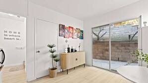 Ein modernes Interieur mit einer weißen Tür, einem Holzschrank und einer Glastür, die in einen Außenbereich führt.
