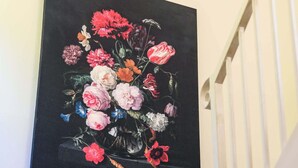 Ein Gemälde einer Blumenanordnung an einer Wand.