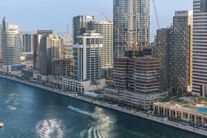 A high-rise building with multiple floors, a waterfront view, and construction cranes nearby. - Stayshort - 1 Bedroom in Business Bay Sleeps 2 With City View (Dubai)