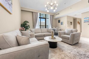 A spacious living area with a beige sofa set, a round coffee table, and a chandelier. - Stayshort - Hidden Jewel in Al Furjan Sleeps 7 (Dubai)