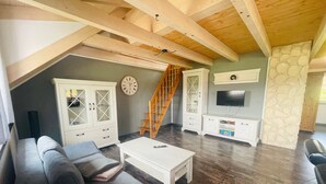 A loft-style living room with a sofa, coffee table, TV, and a staircase. - Allgäunest Apartment with Mountain View, Private Terrace and Wi-Fi (Argenbühl)