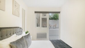 A bedroom with a bed, a window, and a view of the outside. - Shirland Road Flat (London)