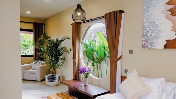 A modern room with a bed, a sofa, a potted plant, and a large window with curtains. - Lux Villa With Outdoor Pool & Garden (Bali)