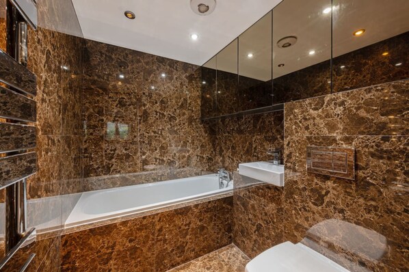 Une salle de bain moderne avec un lavabo en marbre, une baignoire et des toilettes.