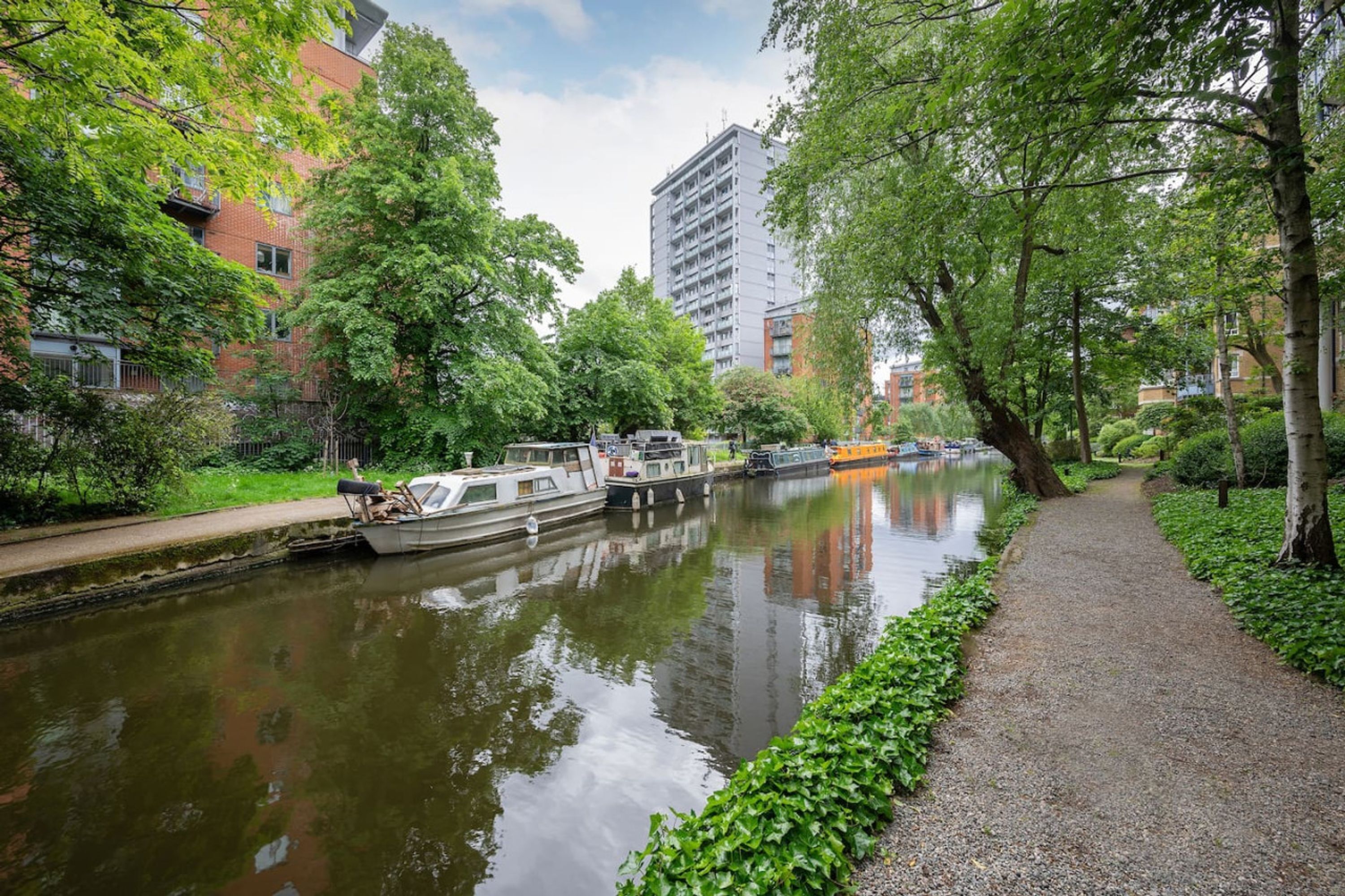Ein Kanal mit Booten, umgeben von Bäumen und Gebäuden.
