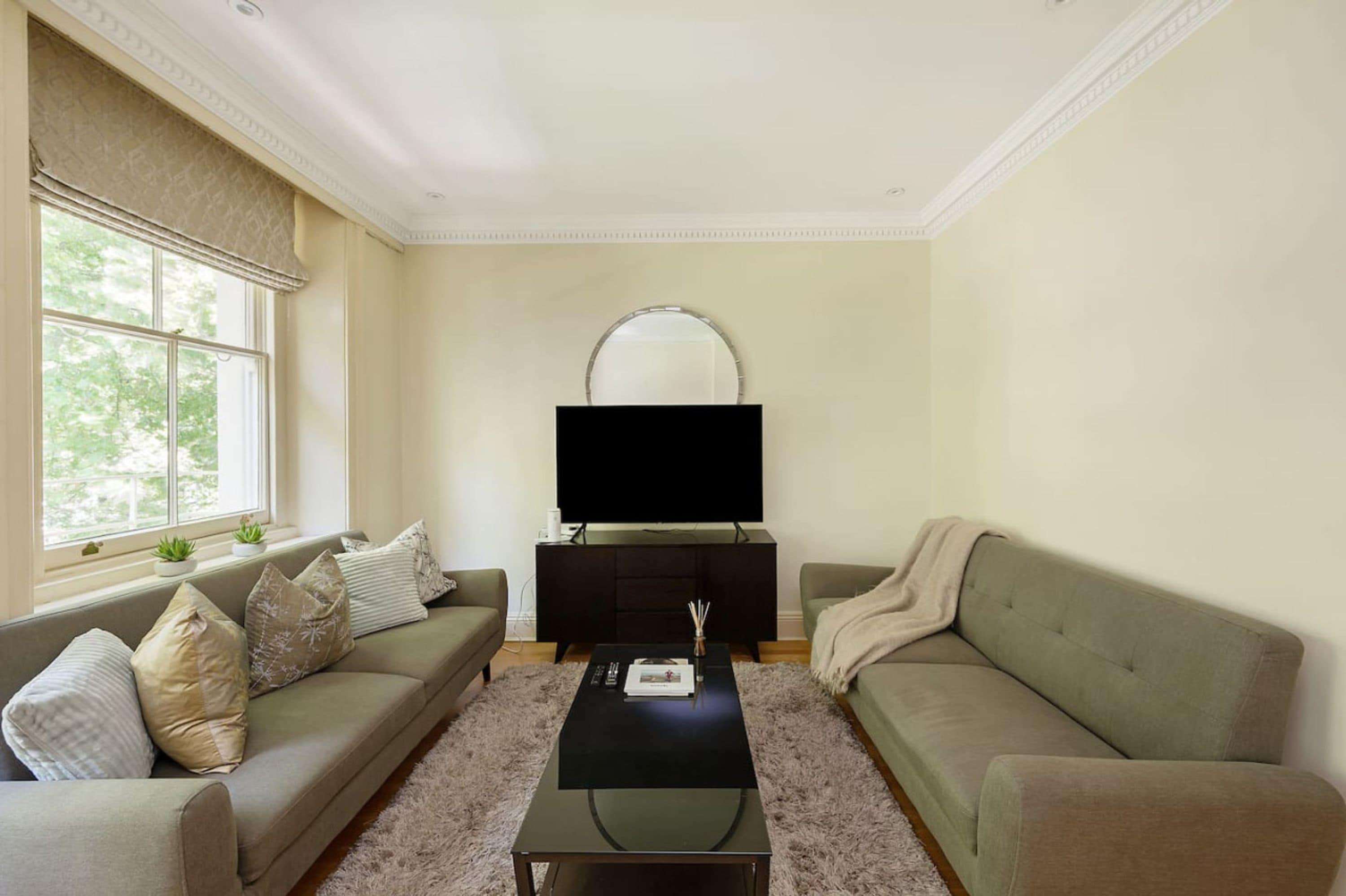 Una sala de estar con un sofá, una mesa de centro y un televisor sobre un mueble.