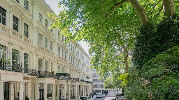 A row of traditional European townhouses with balconies, parked cars, and a tree-lined street. - Luxury Knightsbridge Home Next To Hyde Park (London)