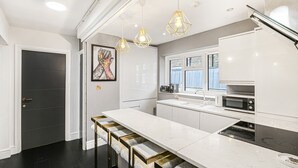A modern kitchen with a central island, pendant lighting, and a view of the outdoors. - Best Location in London 3-bed Chelsea Home (London)