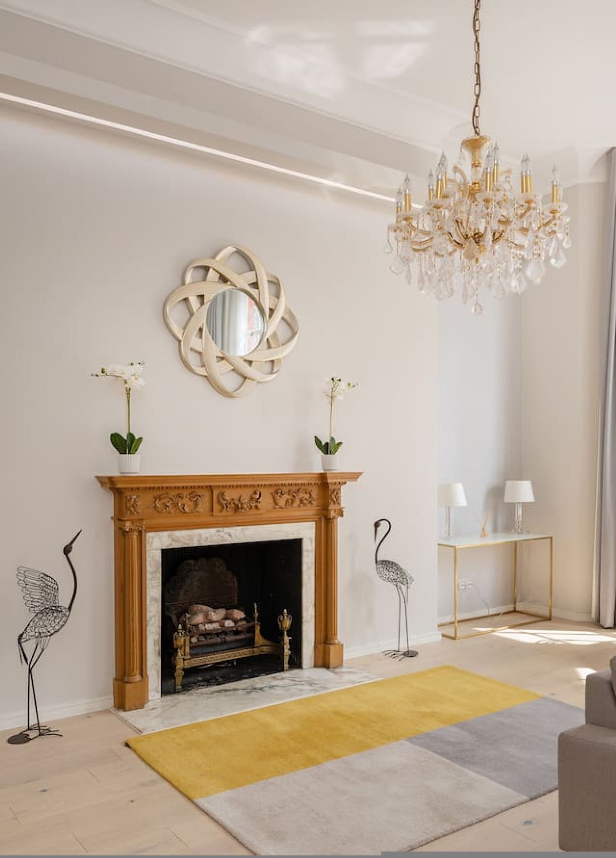 Een moderne woonkamer met een open haard, een kroonluchter en decoratieve muurkunst.