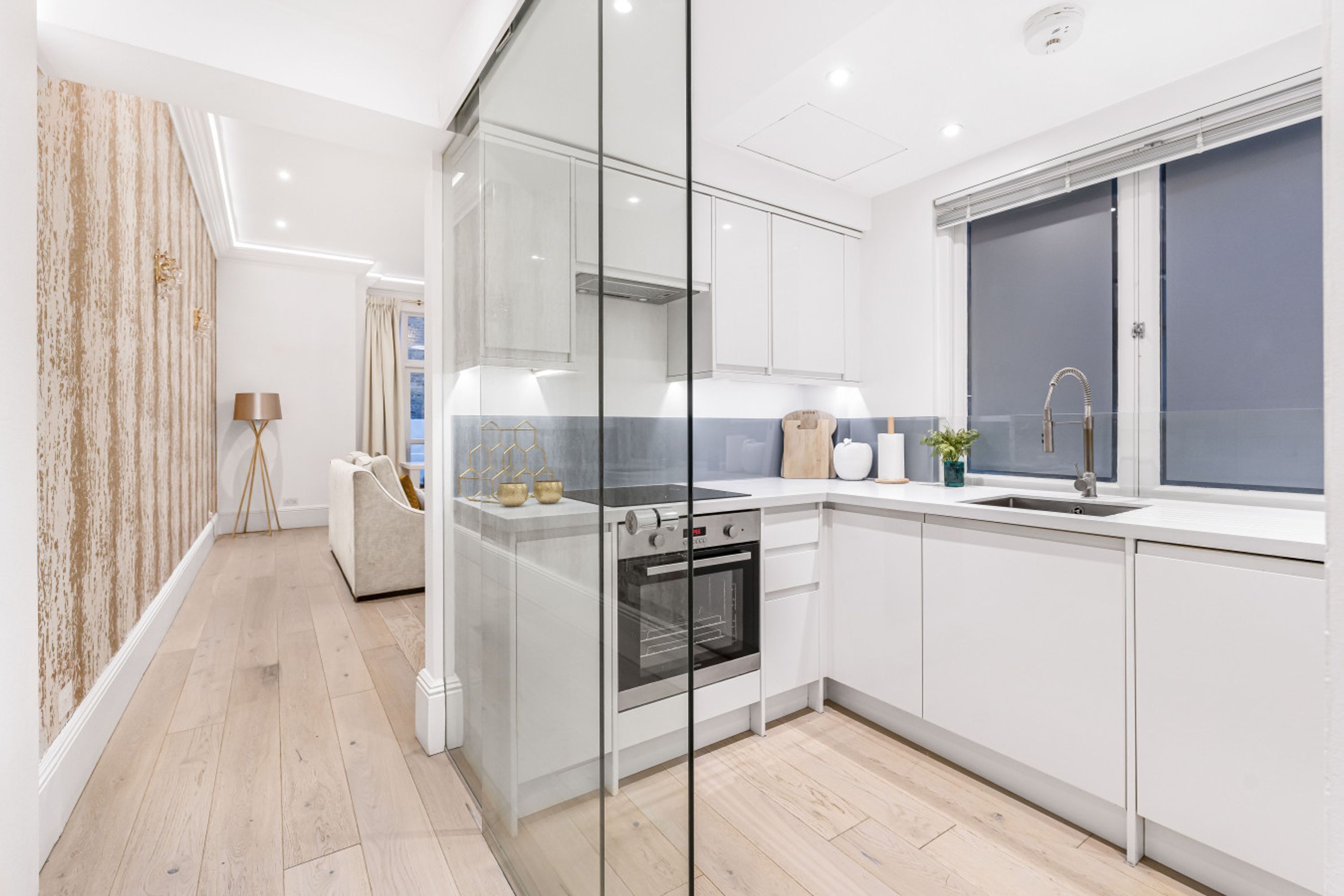 A modern kitchen with white cabinetry, a built-in oven, and a window with a view.
