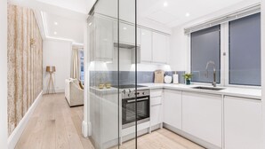 Uma cozinha moderna com armários brancos, forno embutido e janela com vista.