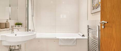 Une salle de bain moderne équipée d’un lavabo, d’un miroir, d’une douche et d’une baignoire.