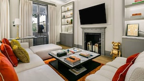 A modern living room with a fireplace, a television, and a bookshelf. - Ultra Luxury Holland Park Home - Central AC (London)