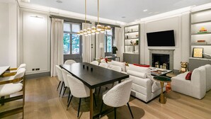 A modern living room with a dining area, a fireplace, and a television mounted on the wall. - Ultra Luxury Holland Park Home - Central AC (London)