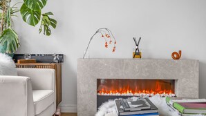 A living room with a fireplace, a sofa, a coffee table with books, and a plant. - 4-bed Knightsbridge Home Gym Cinema Jacuzzi (London)