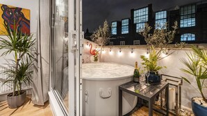 A rooftop terrace with a hot tub, potted plants, and string lights. - 4-bed Knightsbridge Home Gym Cinema Jacuzzi (London)
