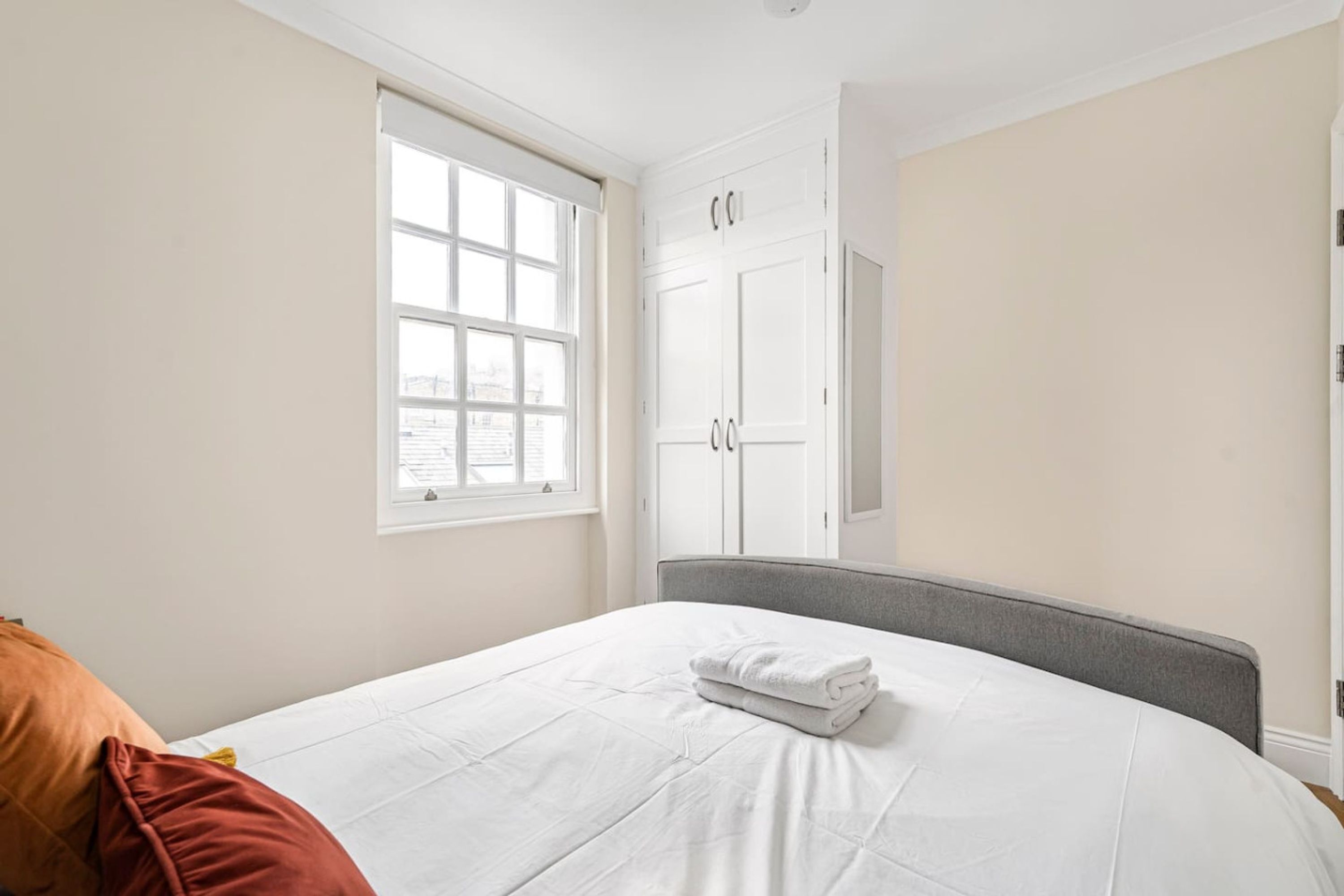 A bedroom with a bed, a window, and a wardrobe.