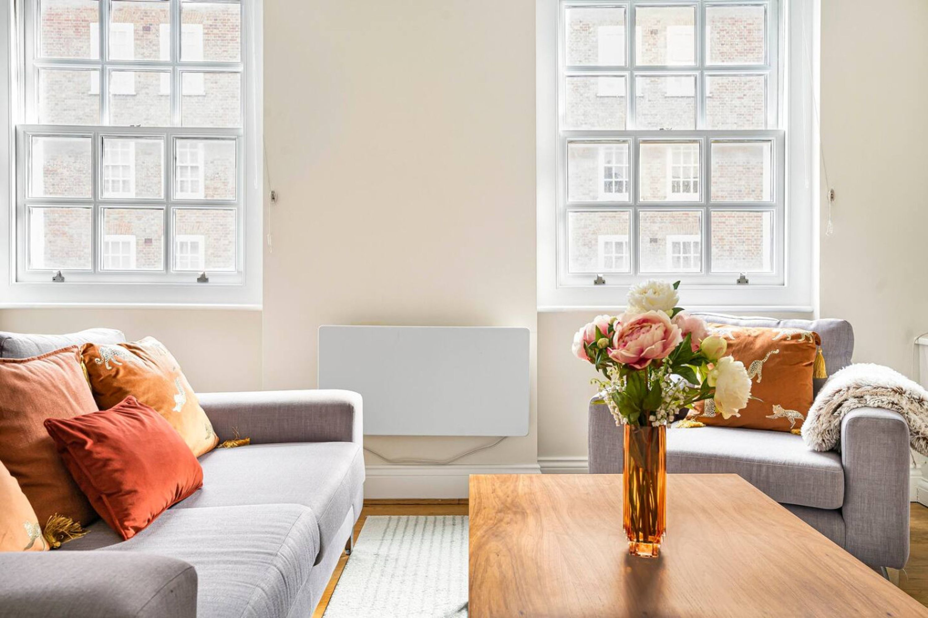 A living room with two sofas, a wooden coffee table, and a vase of flowers.