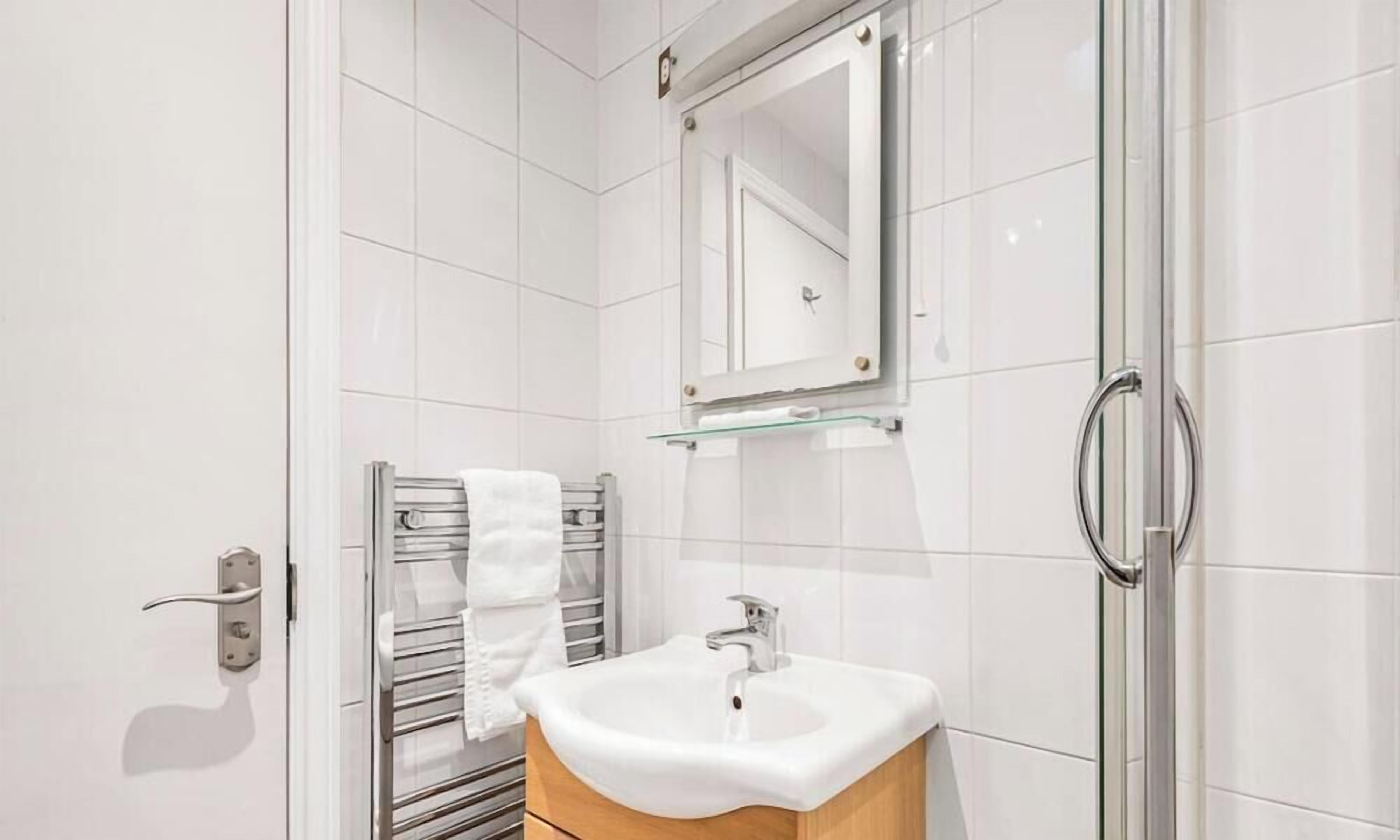 Une salle de bain moderne avec une douche à parois de verre, un lavabo blanc et un porte-serviettes.