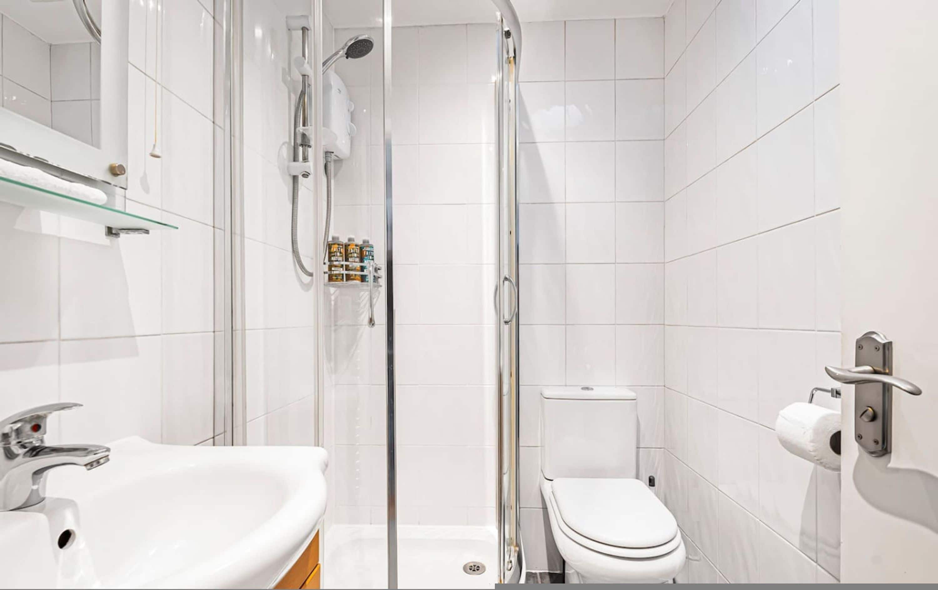 A modern bathroom with a glass-enclosed shower, a white sink, and a toilet.