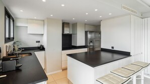 Una cucina moderna con mobili bianchi, un piano di lavoro nero e un'isola integrata con posti a sedere.