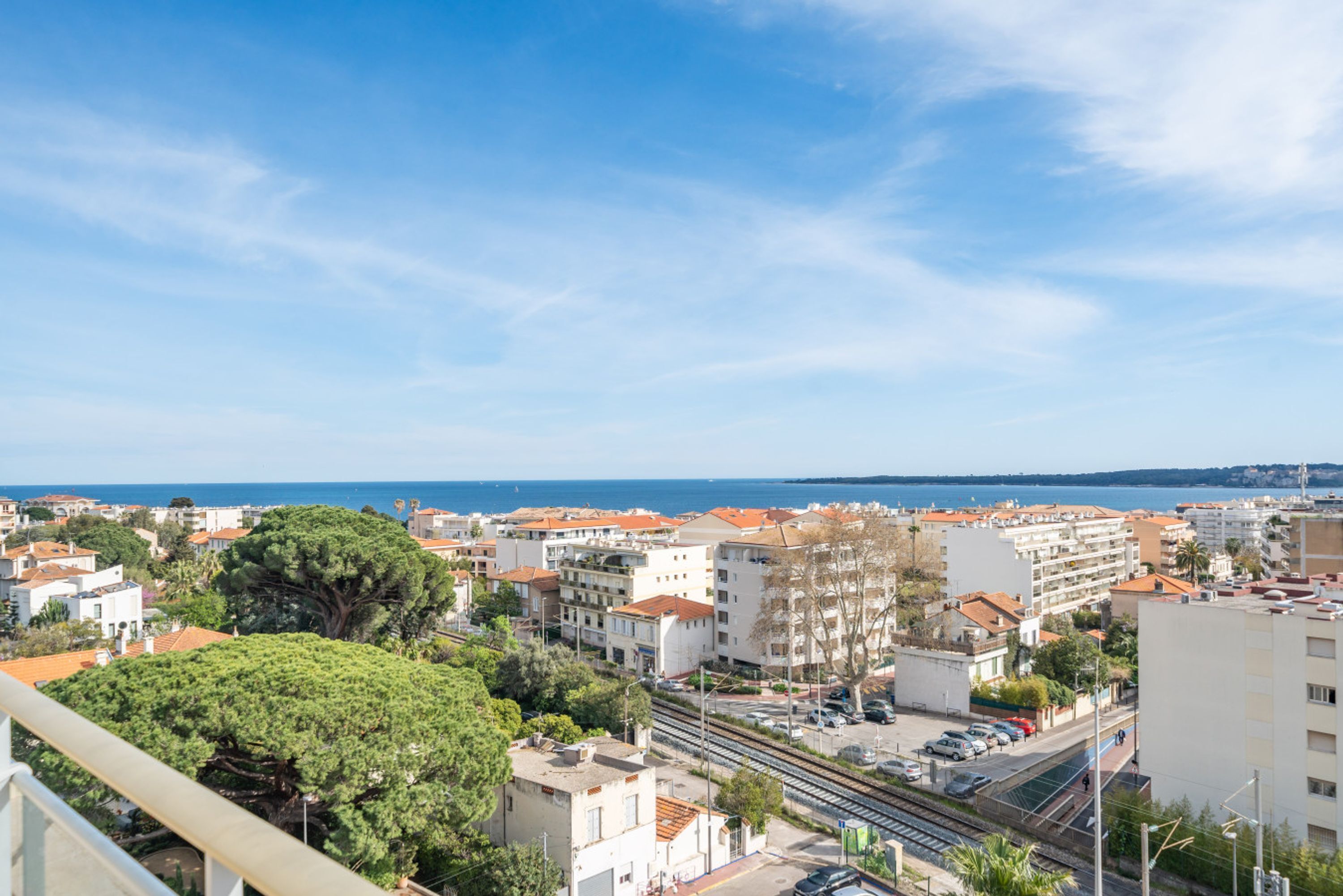 A coastal cityscape with buildings, a train track, and a clear sky.