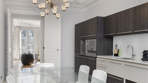Een moderne keuken met donkerhouten kastjes, een glazen eettafel en een wit aanrecht.