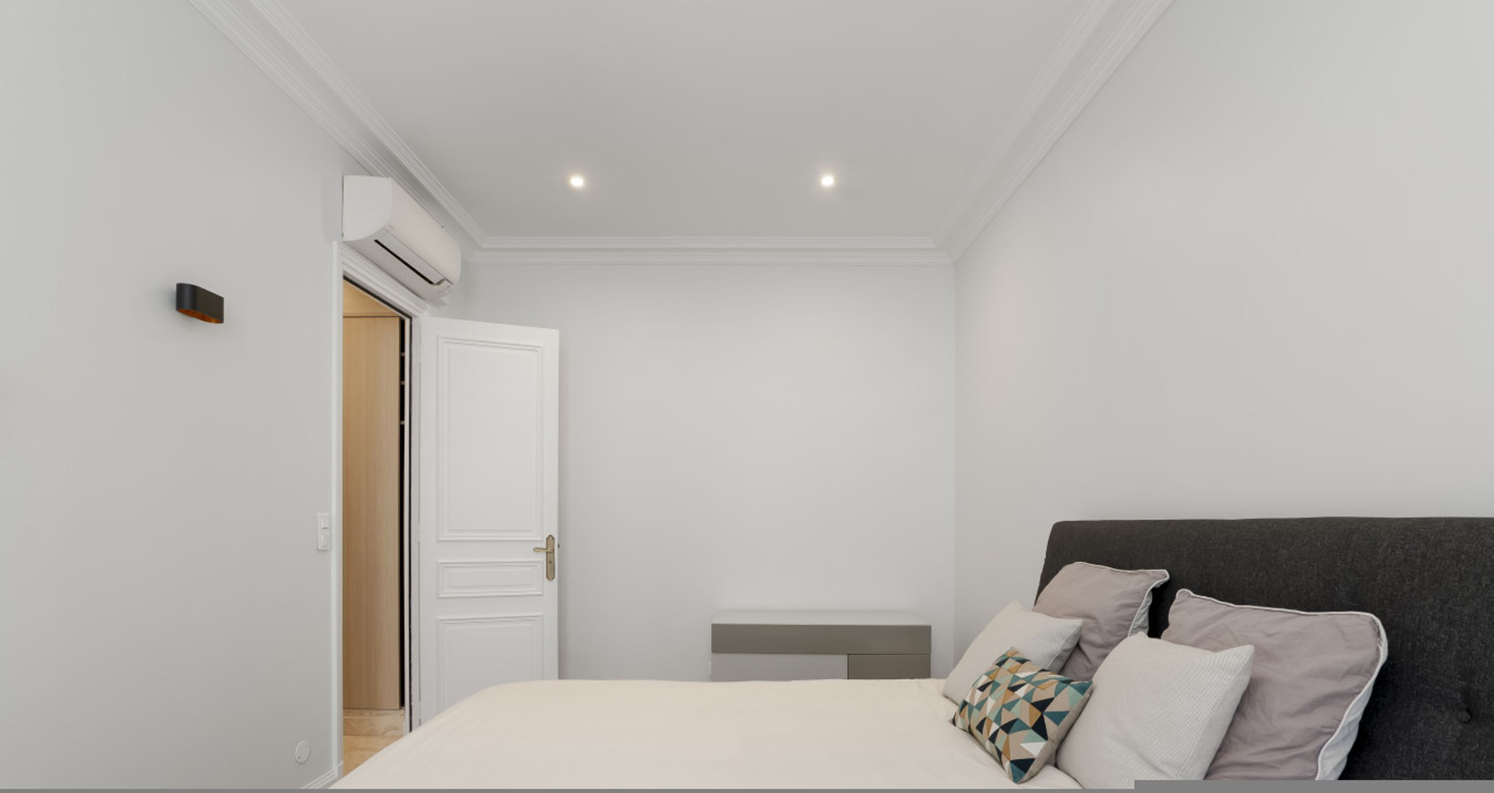 A modern bedroom with a bed, a bedside table, and a wardrobe.